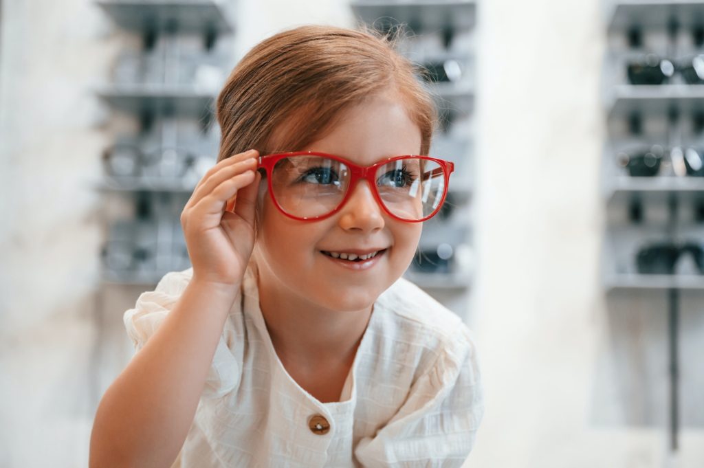 Little girl in the glasses store choosing eyewear